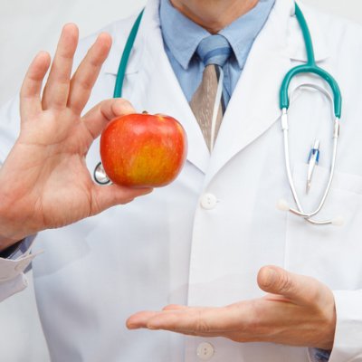 Doctor holding apple and recommending healthy lifestyle